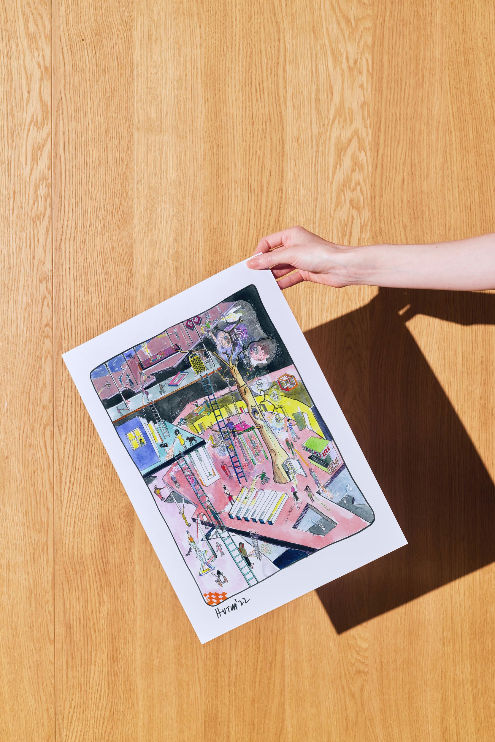 Colorful artwork on paper held by a hand on a wooden surface UCL Child of the New Century commissioned illustration by Jimmy Hutch